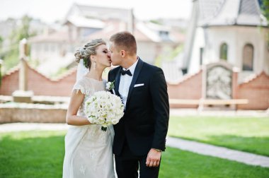 İki şık düğün yürüyor ve yeşil çim üzerinde aşık öpüşme