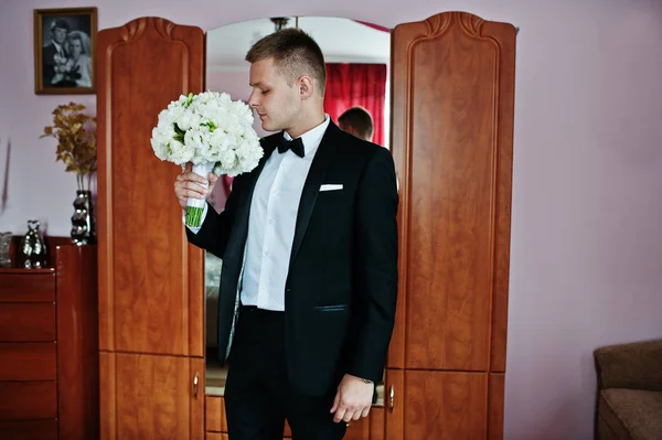 Stylish groom with wedding bouquet at hands on his room. — Stock Photo, Image