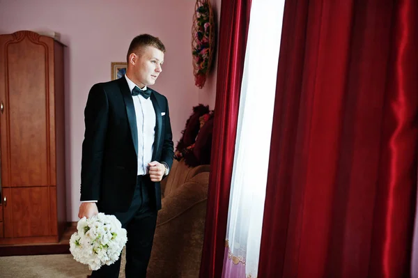 Stylish groom with wedding bouquet at hands on his room. — Stock Photo, Image