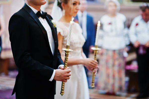 Couple de mariage à l'église avec bougie allumée au chandelier sur h — Photo