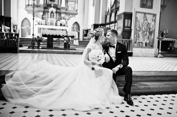 Fotosessie van stijlvolle bruidspaar op de katholieke kerk. — Stockfoto
