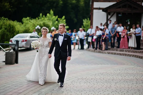 Groom with bride walking to the restaurant against guests at wed — Stock Photo, Image