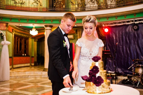 Wedding couple cut golden delicious cake at restaurant. — Stock Photo, Image