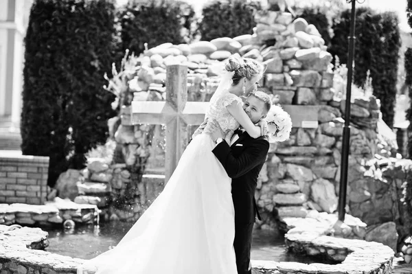 Casal de casamento elegante perto da cruz com fonte . — Fotografia de Stock