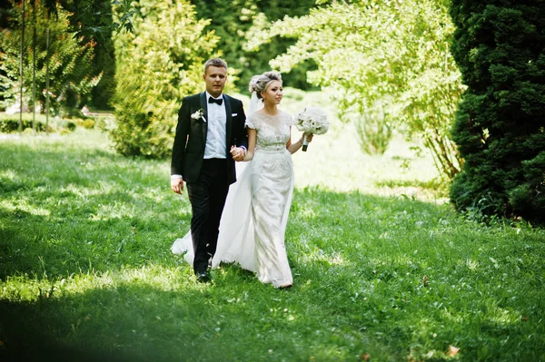 Стильная и шикарная свадебная пара, гуляющая под открытым небом в парке на s — стоковое фото