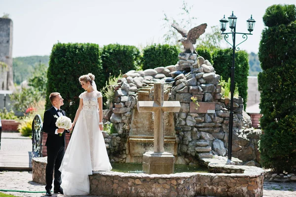 Élégant couple de mariage près de la croix avec fontaine . — Photo