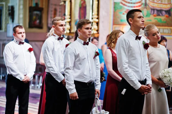 Stijlvolle bruidspaar met bruidsmeisjes en beste mans bij kerk. — Stockfoto