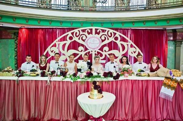 Pareja de boda sentada en la mesa en el restaurante con sus amigos — Foto de Stock