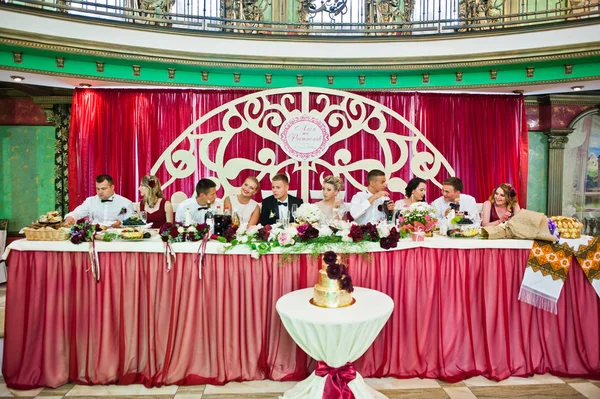 Pareja de boda sentada en la mesa en el restaurante con sus amigos — Foto de Stock