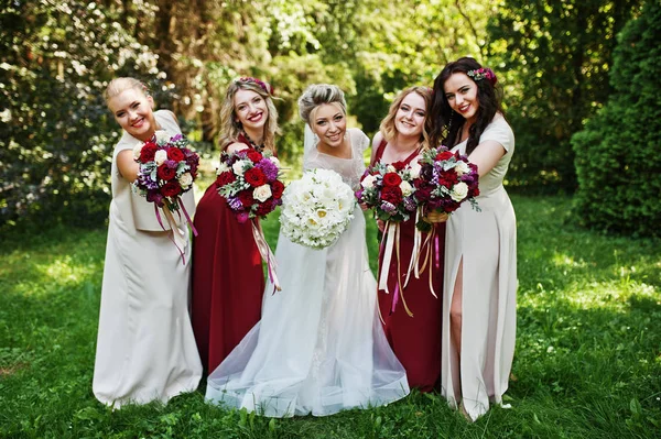 Linda noiva loira com quatro damas de honra no vermelho e bege dre — Fotografia de Stock