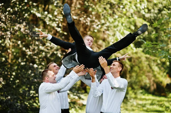 Fashionable groom with four best mans at bow ties outdoor. Frien