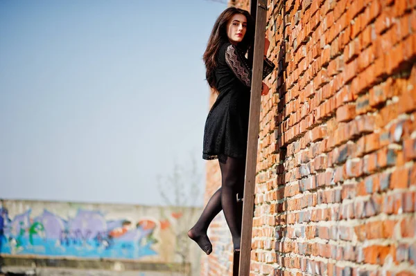 Portrait fille brune avec des lèvres rouges portant une robe noire posée — Photo