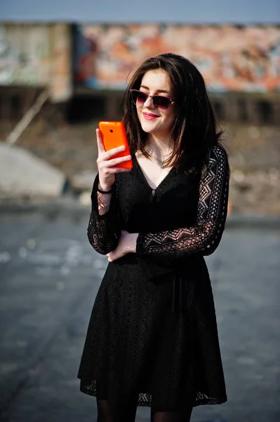 Porträtt brunett tjej med röda läppar och orange mobiltelefon på — Stockfoto