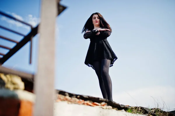 Portrait fille brune avec des lèvres rouges portant une robe noire posée — Photo