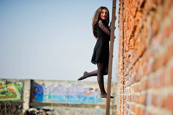 Porträtt brunett tjej med röda läppar som bär en svart klänning som ställde — Stockfoto
