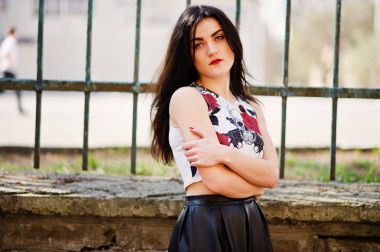 Siyah deri etek demir çit karşı genç goth kız.