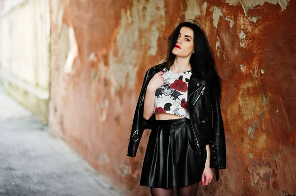 Joven chica gótica en falda de cuero negro y chaqueta contra grunge —  Fotos de Stock