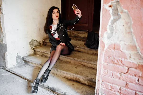 Jeune fille gothique sur jupe en cuir noir et veste assise sur sta — Photo