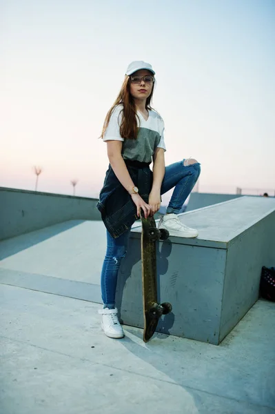 Jeune adolescente urbaine avec skateboard, porter des lunettes, casquette a — Photo