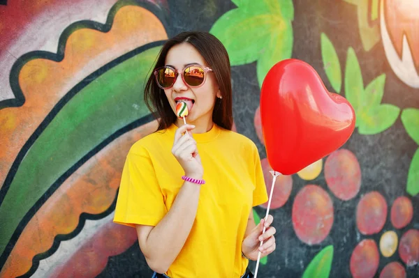 Vacker tonårsflicka slicka lollipop med glasögon, hjärtat bollen — Stockfoto