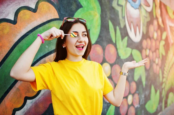 Beautiful teenage med lollipop, bära gul t-shirt nära graffi — Stockfoto