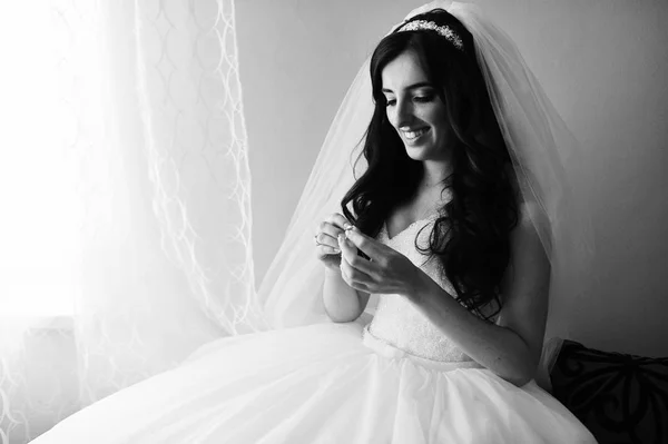 Красива усміхнена брюнетка наречена на весільній сукні біля вікна в — стокове фото