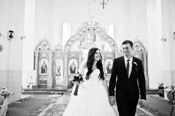 Verheugd huwelijksfeest paar verplaatsen in de kerk, hand in hand. — Stockfoto