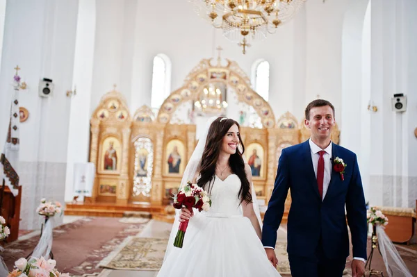 Szczęśliwy ślub para przenosi się w kościele, trzymając się za ręce. — Zdjęcie stockowe