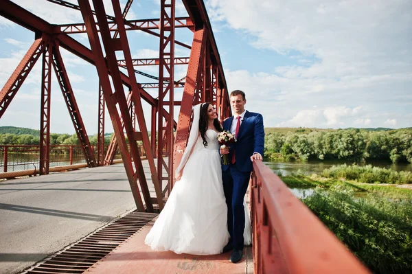 Wedding couple in love stay at red railway bridge. — Stock Photo, Image