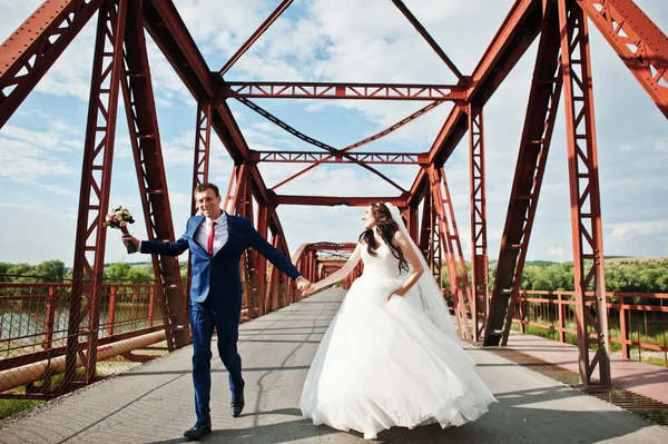 Casamento casal apaixonado ficar na ponte ferroviária vermelha . — Fotografia de Stock