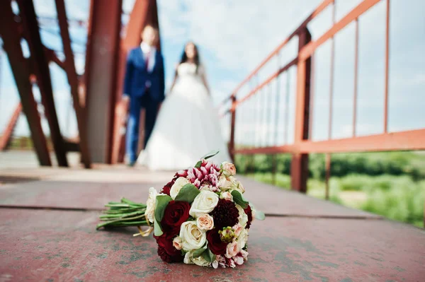 Casamento casal apaixonado ficar na ponte ferroviária vermelha . — Fotografia de Stock