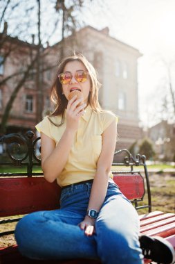 Dondurma elinde, wea bankta oturan genç genç kız