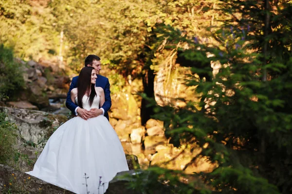 Lovely wedding couple against river with stones at Carpathian mo — Stock Photo, Image