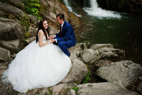 Hermosa pareja de boda contra la cascada al atardecer en Carpathian —  Fotos de Stock