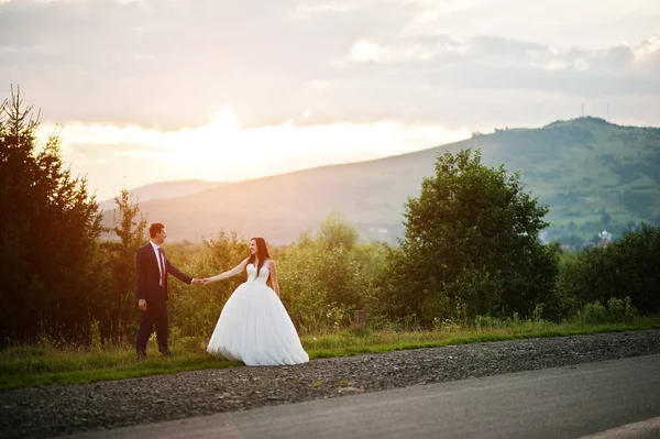 Beau couple de mariage contre le coucher du soleil dans les Carpates . — Photo