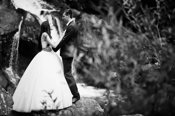 Hermosa pareja de boda contra la cascada al atardecer en Carpathian —  Fotos de Stock