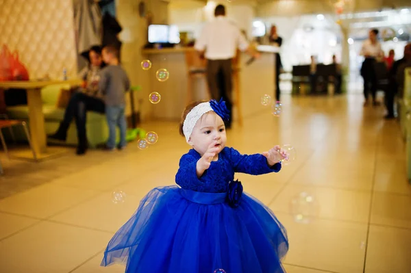 Söt liten baby flicka i blå klänning leker med såpbubblor. 1 ni — Stockfoto