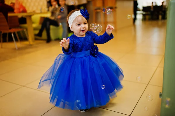 Söt liten baby flicka i blå klänning leker med såpbubblor. 1 ni — Stockfoto