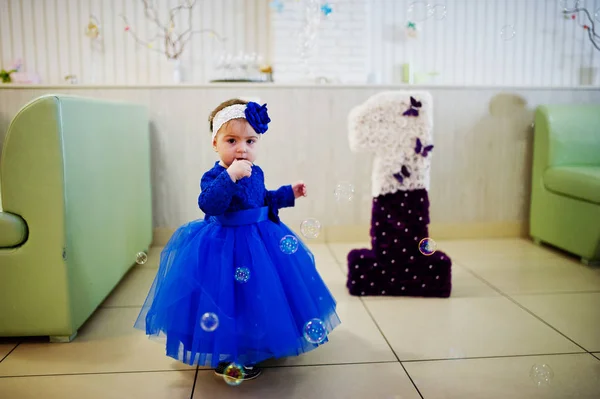 Söt liten baby flicka i blå klänning leker med såpbubblor. 1 ni — Stockfoto