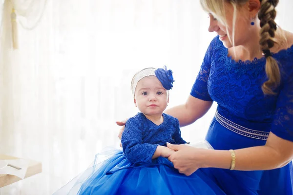 Roztomilá malá holčička v modrých šatech na ruce matky. — Stock fotografie