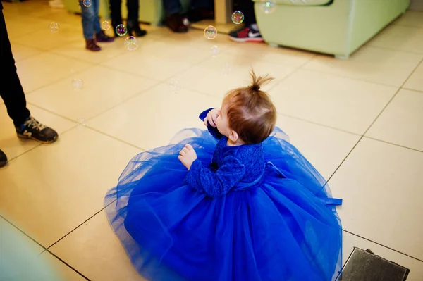 Söt liten baby flicka i blå klänning leker med såpbubblor. 1 år födelsedag dag. — Stockfoto