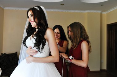 Mutlu neşeli esmer gelin odasına iki gelinle giyiyor