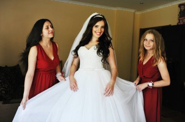 Mutlu neşeli esmer gelin odasına iki gelinle giyiyor