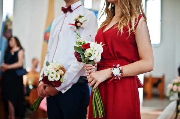 Las manos de las damas de honor a los vestidos rojos con el ramo de boda en chur — Foto de Stock