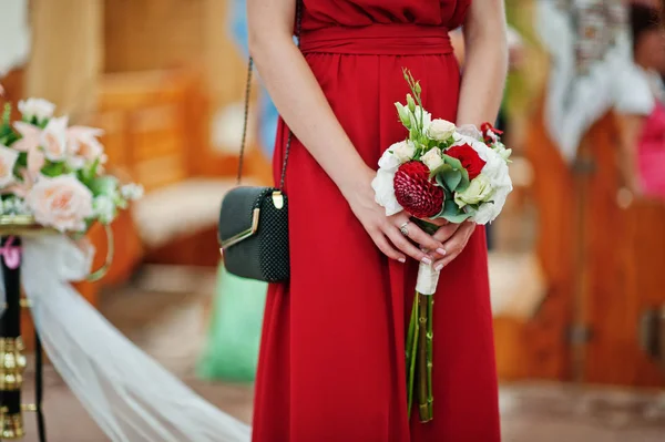 Руки подружек невесты в красных платьях со свадебным букетом на чур — стоковое фото