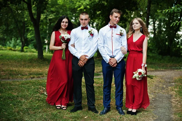 Bruidsmeisjes op rode jurken met groomsman of bruidsjonker op bruiloft — Stockfoto