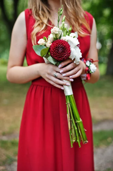 Bonito dama de honra menina no vestido vermelho com buquê de casamento na mão . — Fotografia de Stock