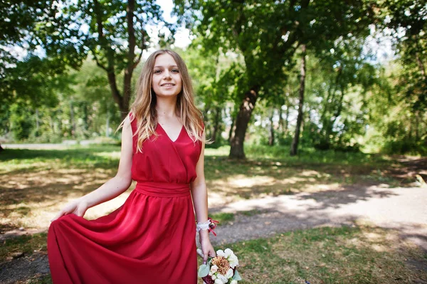 Милая девушка-подружка невесты в красном платье со свадебным букетом под рукой . — стоковое фото
