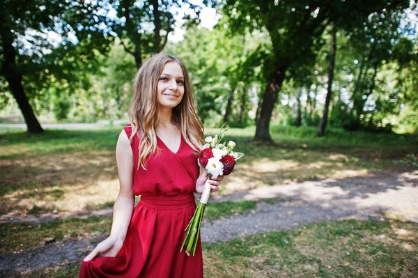 Söt flicka brudtärna på röd klänning med bröllop bukett till hands. — Stockfoto