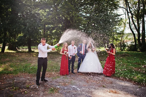 Pasangan pengantin dengan pengiring pengantin dan pria terbaik minum sampanye — Stok Foto